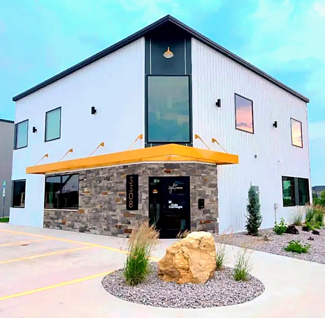 White commercial building with a stone base and yellow awning